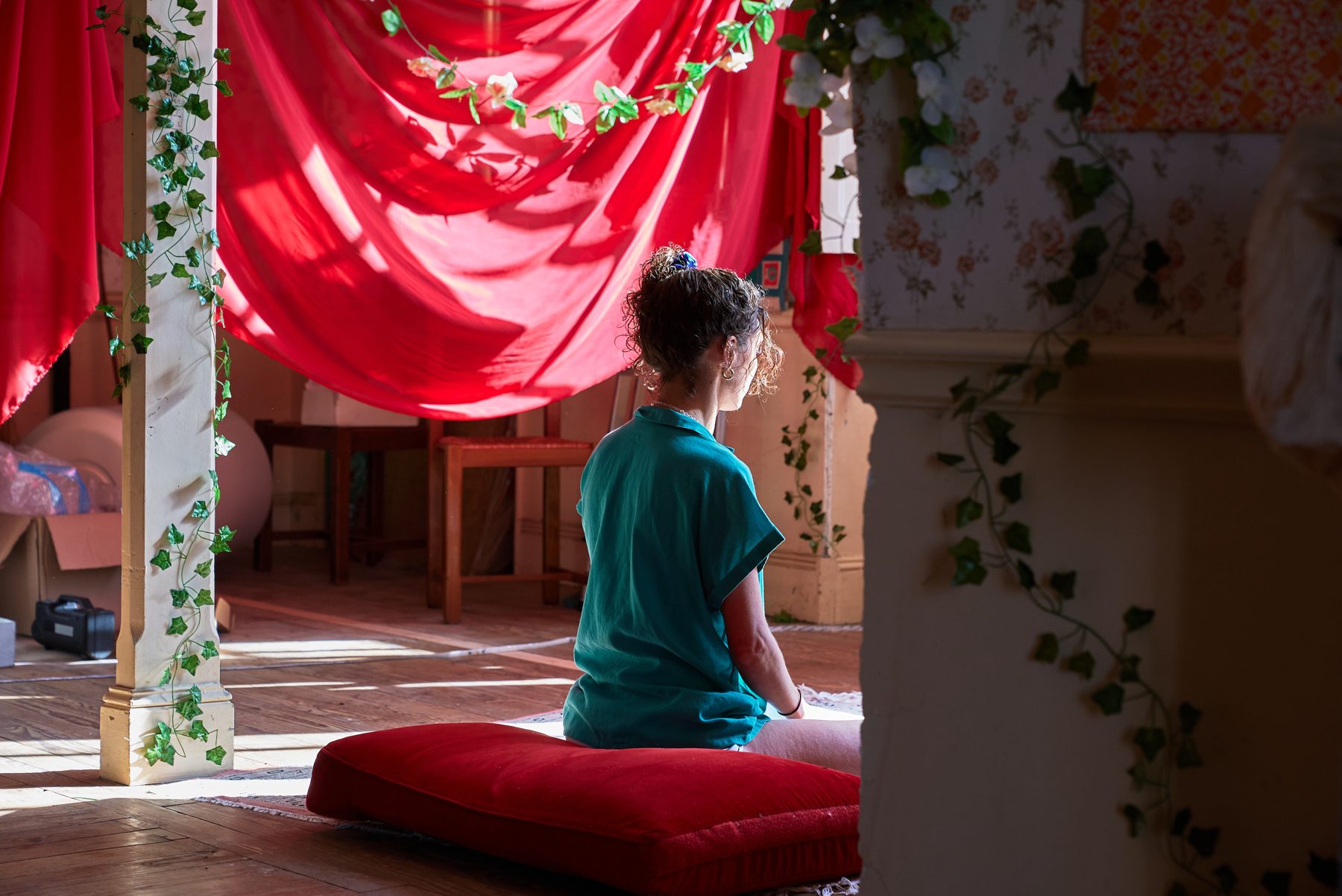 Une personne assise de dos, en pratique méditative dans la salle de la maison