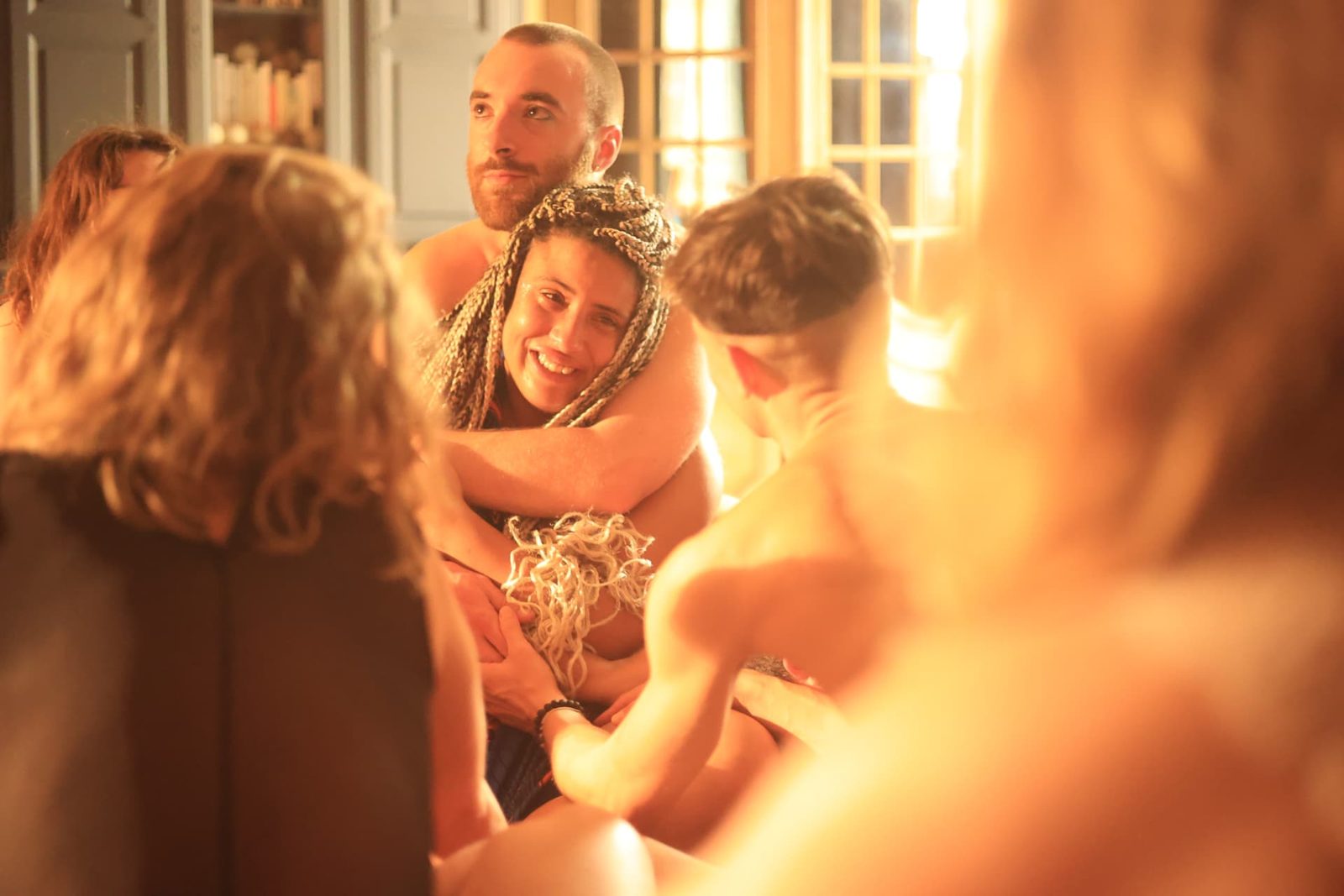 Un cercle de personnes enlacées dans la lumière chaude du salon