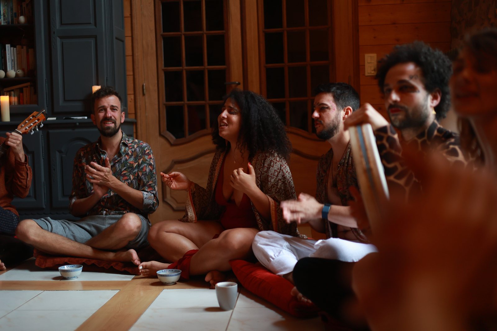 Un cercle de participant·es chantant autour d'une guitare dans le salon
